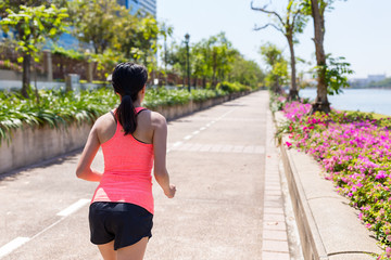 Back view of woman running at green park