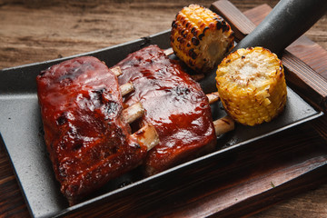 Appetizing grilled pork ribs with corn served on shovel. Restaurant menu photo. American cuisine. Junk food, picnic, bbq concept