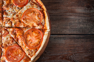 Fresh italian pizza with tomatoes, ham and cheese on wooden table. Top view with free space for text. Restaurant menu photo.