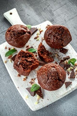 Brown muffins with dark chocolate chippings on white wooden board