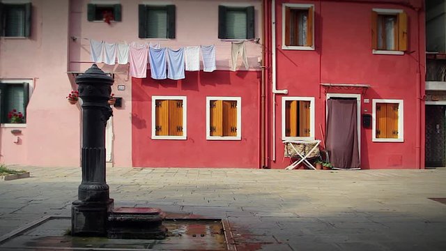 Water pump and the puddle around with colorful houses on background
