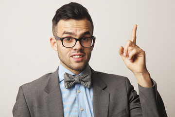 Smiling young man  pointing upwards with her finger towards copy space area