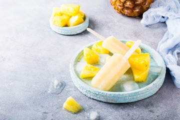 Delicious homemade pineapple popsicles on light blue plate on gray background. Summer food concept with copy space. High angle view.