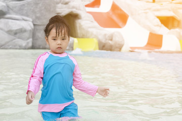 Children play in the swimming pool or water park with water slides on summer holiday and sunlight, soft focus