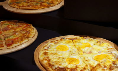 egg with chili meat and ham pizza on the wood tray and black counter bar for dinner food in the restaurant on warm white