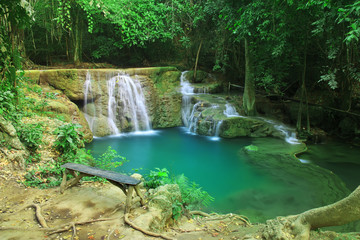 waterfall with relax long wood chair and clear blue and green emerald water with tree and root in the jungle at Huay Mae Khamin waterfall for nature landscape and background