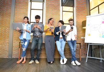 Group of businesspersons with age variety holding electronic devices and gadgets in the office