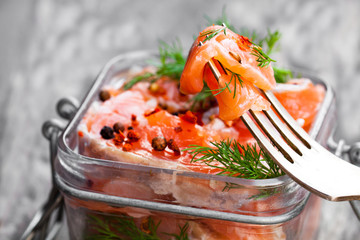 Salted  salmon with herbs in glass jar on wooden background