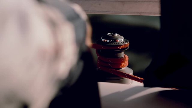 Traveling by sea on the ship. Close-up view of man using the capstan head to fixing the rope.