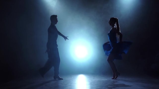 Professional couple of ballroom dancers posing in smoky, slow motion
