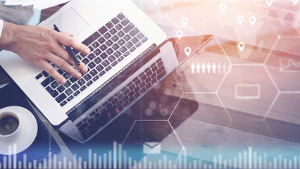 Closeup of digital screen,virtual connection icon,diagram,graph interfaces.Man working with laptop at office.Modern mobile computer,cup of black coffee on wooden table.Sunlight effect glass surface.