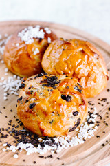 Three Fresh Buns Decorated With Sugar And Chocolate On A Wooden Board