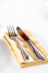 Fork and knife laying on a napkin on the table.