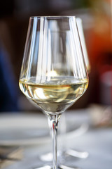 A glass of white wine stands on the table in the restaurant.
