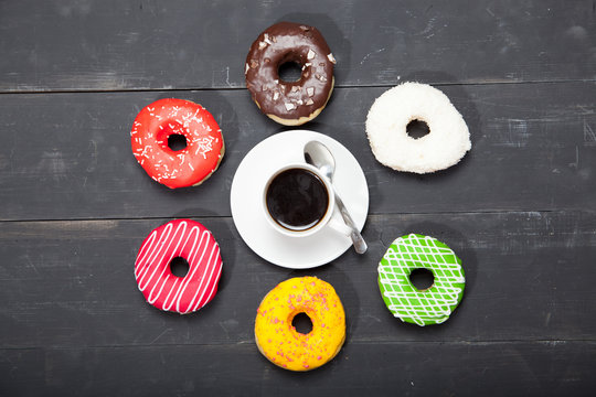 Cup with coffee and donuts on a black wooden table