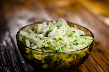 Salad with the cabbage and green onion on wooden table
