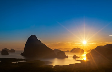 Fototapeta na wymiar beautiful sunrise over island mountain with yellow color sunlight shine dawn on forest beach