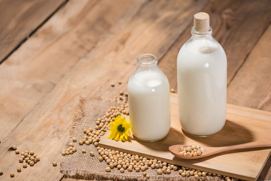 A bottle of soy milk or soya milk and soy beans on wooden table.