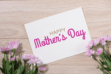 Pink flowers and empty paper for your text on wooden background