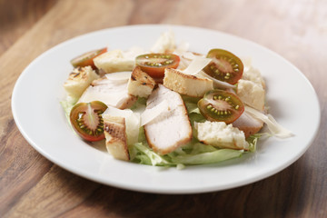 caesar salad with cherry kumato tomatoes on wooden table, homemade dish