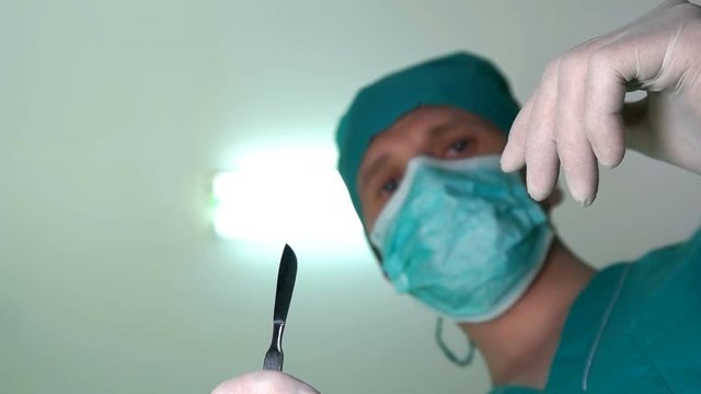 The surgeon starts to operate with a scalpel in his hands