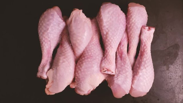 Process of defrosting chicken drumsticks in a timelapse view from above on a black background