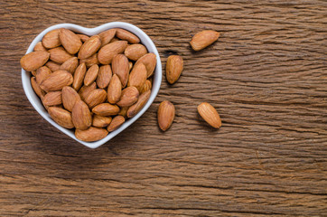 almond in porcelain heart bowl on wooden board