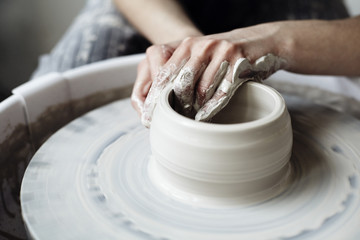 The woman's hands close up, the masterful studio of ceramics works with clay on a potter's wheel - obrazy, fototapety, plakaty