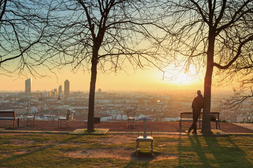 Man in a park in Lyon, enjoying the sunrise over the city.