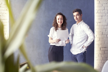 Two young professionals or students woman man happy with business meeting, smiling and talking about project. Office blue wall background