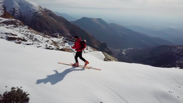 Ski mountaineer walks uphill on a snowy ridge. European Alps, Valle d'Aosta, Italy. 4K UHD aerial shot. Graded footage.