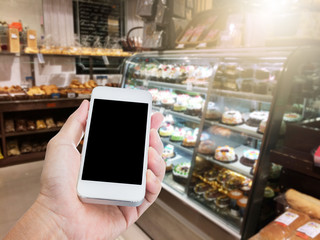 Hand holding mobile phone with blur coffee shop background