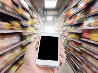 Hand holding mobile phone with blur supermarket shelf background