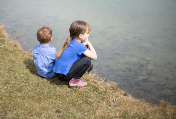 Fototapeta premium Siblings sitting by the lake.