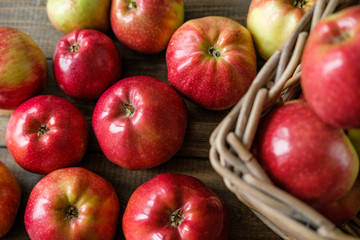 basket with red ripe apples on a brown wooden table