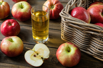 A glass of juice on a background of red ripe apples