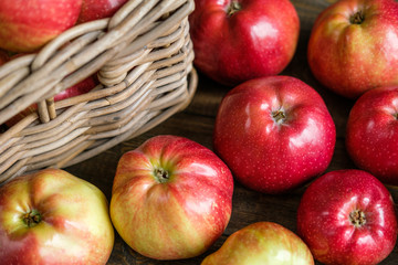basket with red ripe apples on a brown wooden table