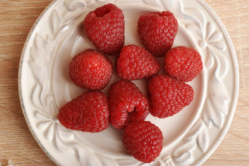 fresh red raspberries on a plate top view