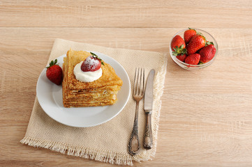 pancakes with sour cream and strawberries in a plate