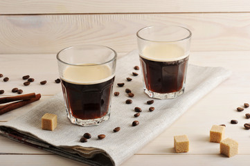 two mugs of coffee on a linen napkin and coffee beans with sugar and cinnamon