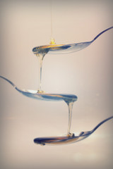 Honey pouring from spoon against a light background