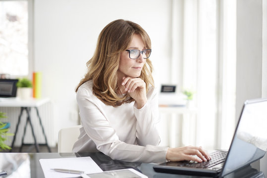 Confident professional woman. Shot of an attractive mature businesswoman working on laptop in her workstation.