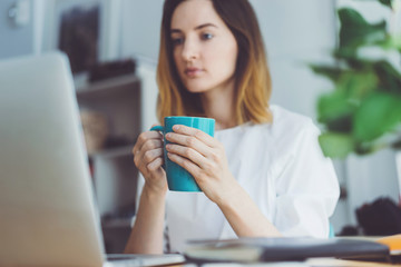 Young businesswoman working at modern office on portable computer, Attractive female drinking coffee while working at office