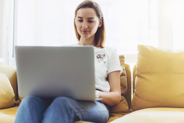 Young attractive business woman working on new project and siting on cozy sofa, Hipster girl working on a portable compute from home