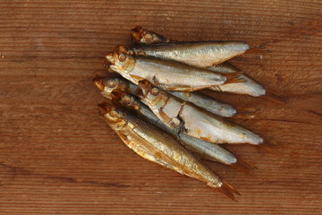 Haufen frisch gefangener Sprotten auf Holzbrett