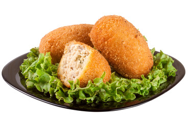 three fried breaded cutlet with lettuce on a black plate isolated white background