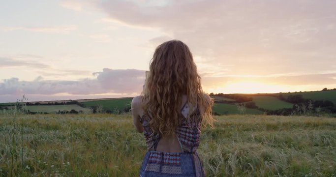 Rear view of attractive red head woman taking panorama photographing wheat field using smartphone capturing epic nature background Cornwall, UK