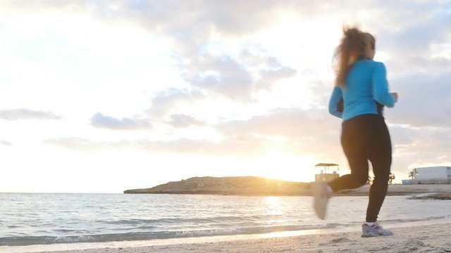 Young athletic woman running along the beach