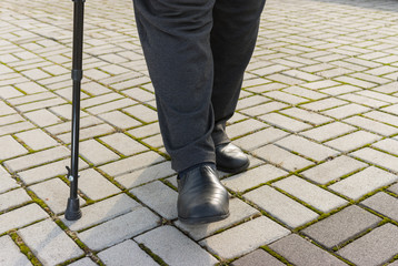 Man with walking stick doing hard step on a pavement