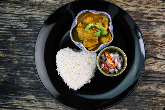Asian food. Yellow Curry Chicken in Coconut Milk With Rice on wooden background